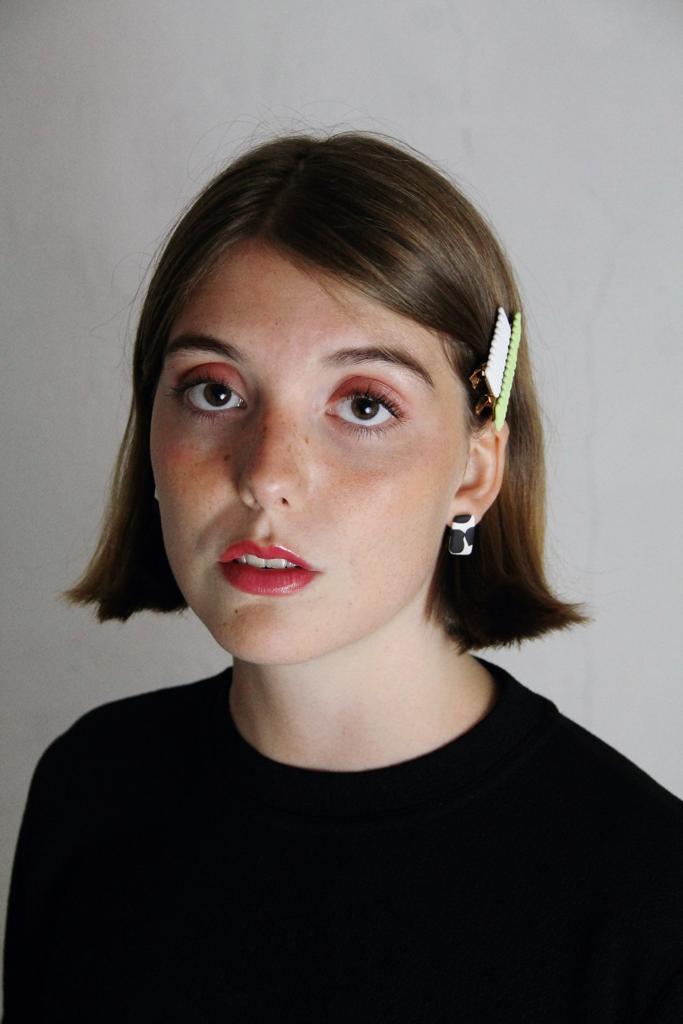 Model wears minimalist earrings in cow marble print. She also wears handmade hair pins in the shape of a bow.