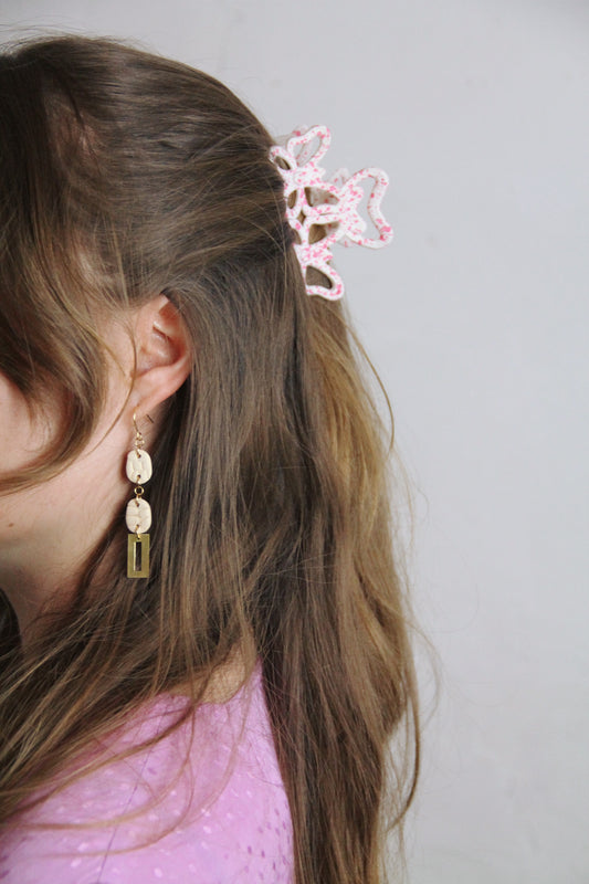 Gorgeous young woman wearing the Beth earrings in beige with a radiant brass element by the brand Dress To Finesse. This brand is created by Anna De Ceulaer in Antwerp, Belgium. The Beth earrings are made of clay and are very lightweight.