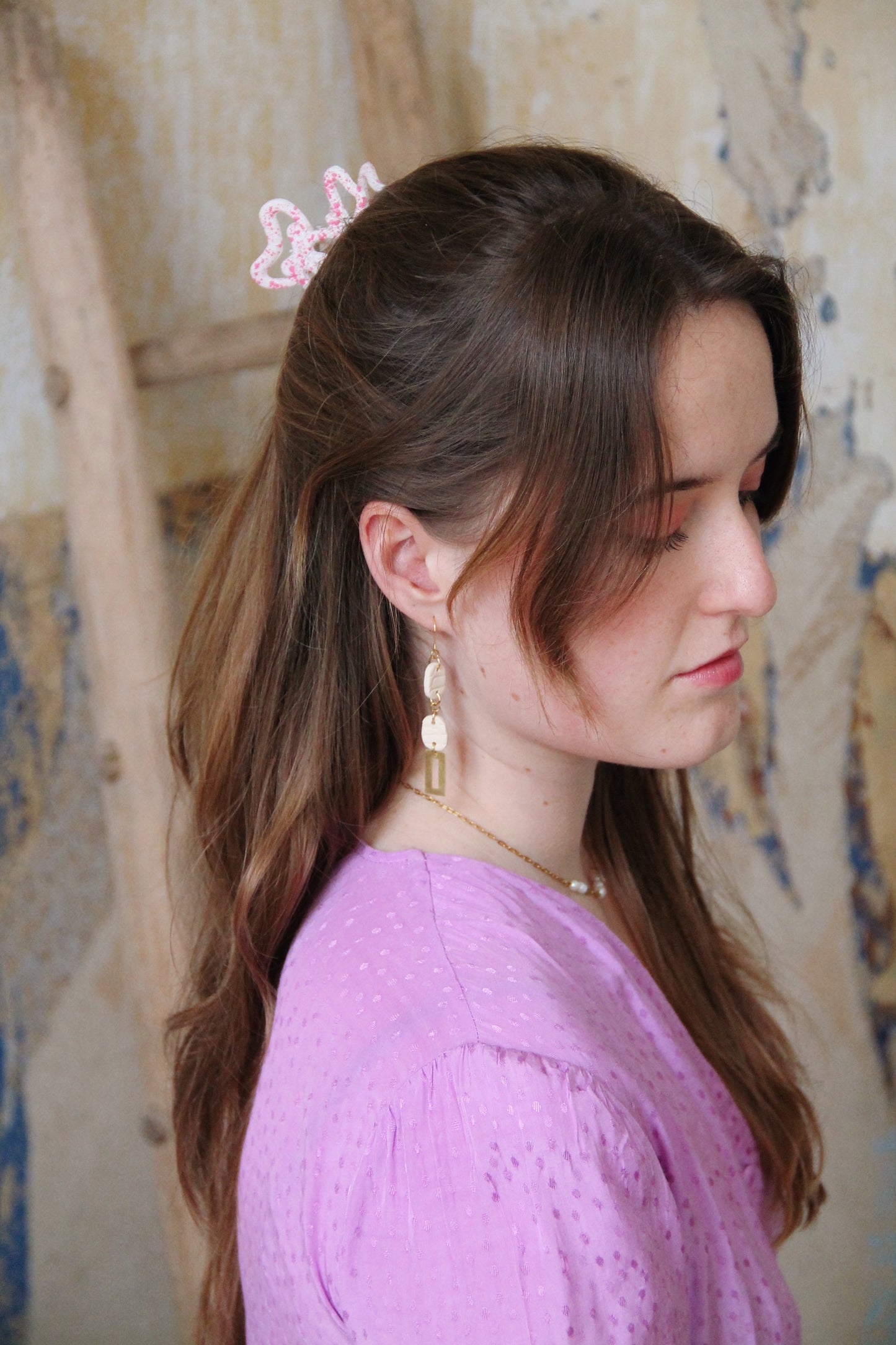 Gorgeous young woman wearing the Beth earrings in beige with a radiant brass element by the brand Dress To Finesse. This brand is created by Anna De Ceulaer in Antwerp, Belgium. The Beth earrings are made of clay and are very lightweight.