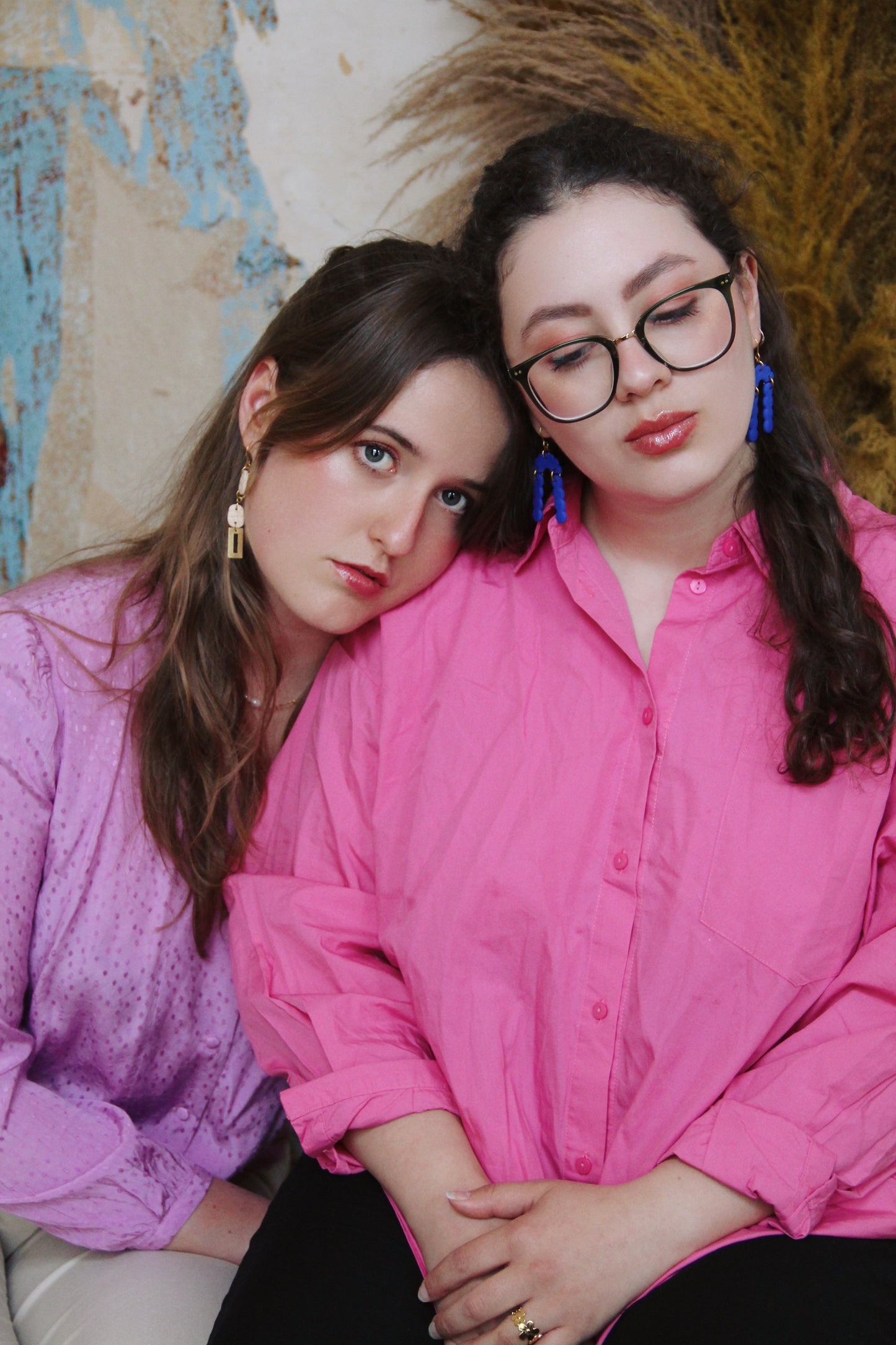 Gorgeous young woman wearing the Beth earrings in beige with a radiant brass element by the brand Dress To Finesse. The other girl on the right is wearing the Elisabeth earrings in royal blue. This brand is created by Anna De Ceulaer in Antwerp, Belgium. The Beth earrings are made of clay and are very lightweight.