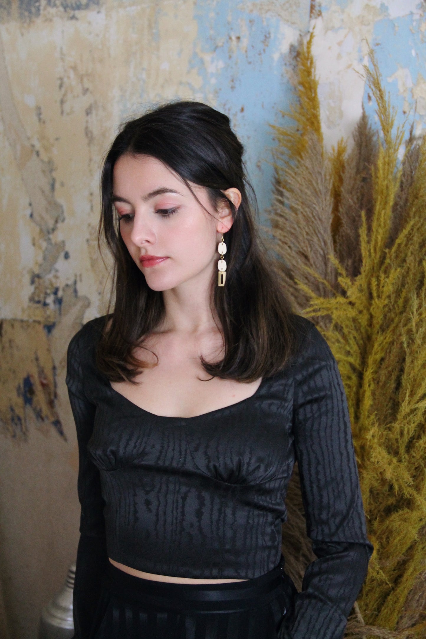 Gorgeous young woman wearing the Beth earrings in beige with a radiant brass element by the brand Dress To Finesse. This brand is created by Anna De Ceulaer in Antwerp, Belgium. The Beth earrings are made of clay and are very lightweight.