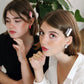 Models wear minimalist earrings in black and white marble print and in pink and red marble print. They also wear handmade hair pins in the shape of a bow.