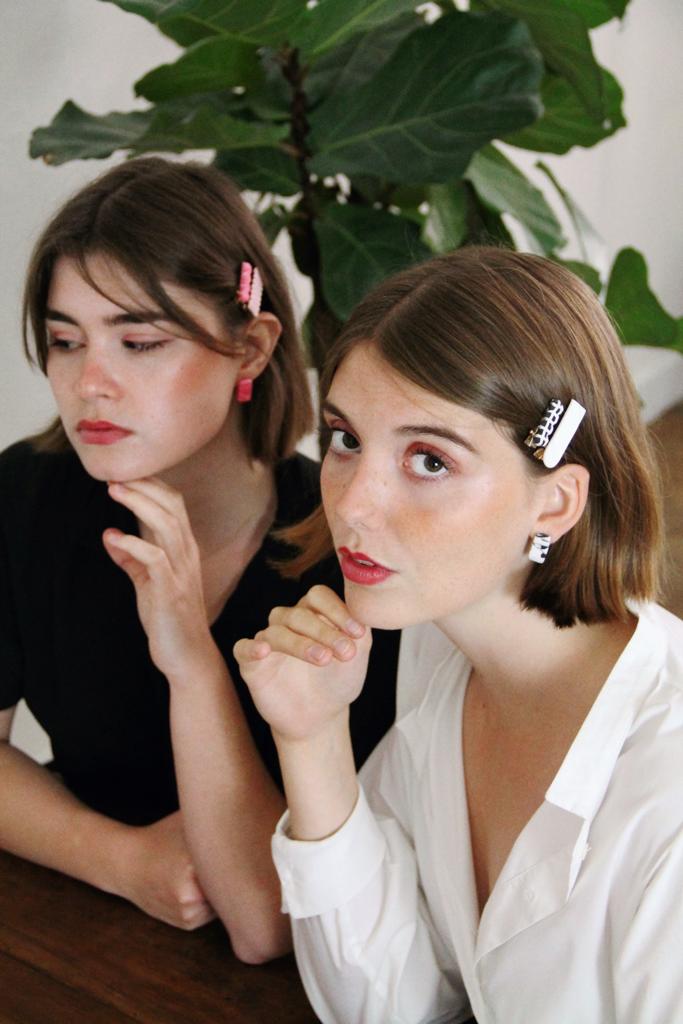 Models wear minimalist earrings in black and white marble print and in pink and red marble print. They also wear handmade hair pins in the shape of a bow.