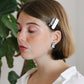 Model wears minimalist earrings in black and white marble print. She also wears handmade hair pins in the shape of a bow.