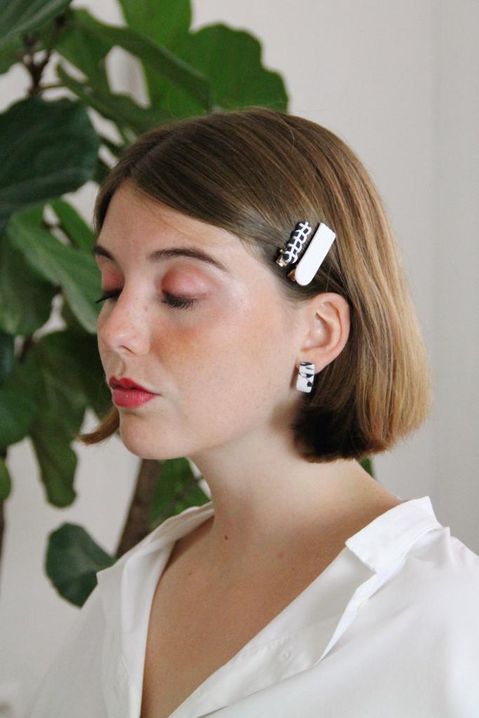 Model wears minimalist earrings in black and white marble print. She also wears handmade hair pins in the shape of a bow.