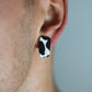 Model wears minimalist earrings in cow print. He also wears handmade hair pins in the shape of a bow.