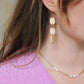 Gorgeous young woman wearing the Beth earrings in beige with a radiant brass element by the brand Dress To Finesse. This brand is created by Anna De Ceulaer in Antwerp, Belgium. The Beth earrings are made of clay and are very lightweight.