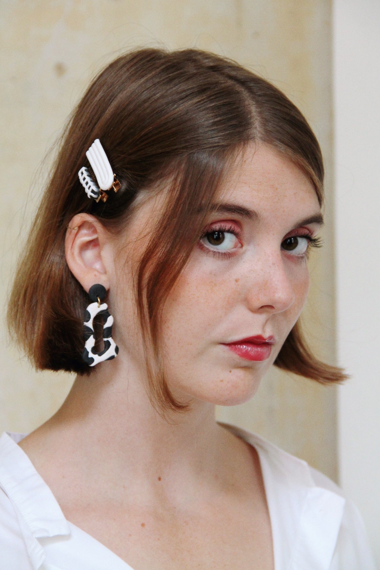 Gorgeous young woman wearing the ANNA earrings in cow print by the brand Dress To Finesse. This brand is created by Anna De Ceulaer in Antwerp, Belgium. The ANNA earrings are made of clay and are very lightweight. The model is wearing the DAEN hair clips in matching colours.
