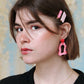 Gorgeous young woman wearing the ANNA earrings in pink by the brand Dress To Finesse. This brand is created by Anna De Ceulaer in Antwerp, Belgium. The ANNA earrings are made of clay and are very lightweight. The model is wearing the daen and kiki hair clips in matching colours.