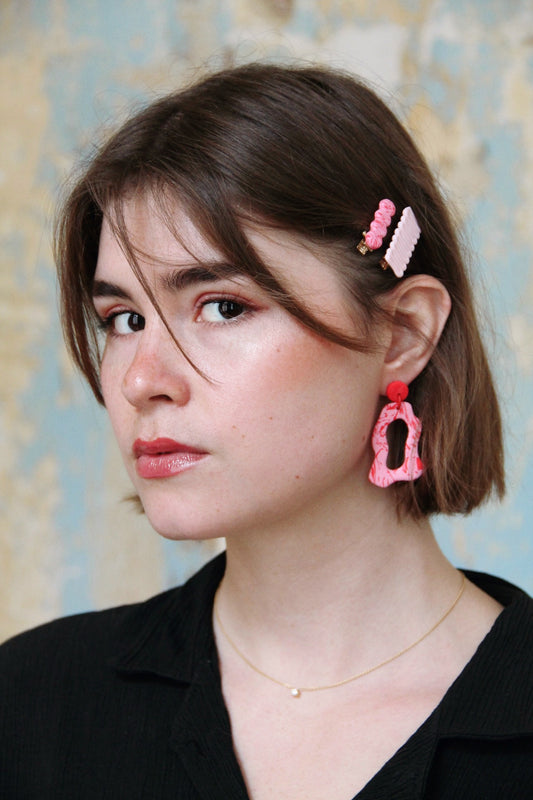 Gorgeous young woman wearing the ANNA earrings in pink by the brand Dress To Finesse. This brand is created by Anna De Ceulaer in Antwerp, Belgium. The ANNA earrings are made of clay and are very lightweight. The model is wearing the daen and kiki hair clips in matching colours.